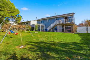 Back of house with stairway, a wooden deck, a playground, and a gate