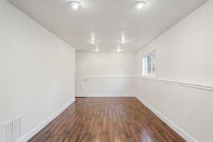 Spare room featuring dark wood-style floors and baseboards