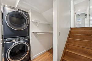 Washroom featuring stacked washing machine and dryer, light wood finished floors, and recessed lighting
