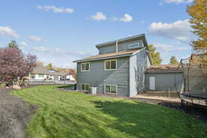 Back of property with a trampoline and a shingled roof