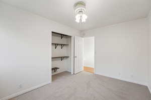 Unfurnished bedroom with ornamental molding, light colored carpet, and a walk in closet