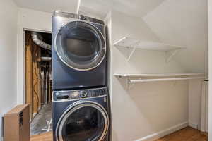 Laundry area with light wood finished floors and stacked washer / drying machine