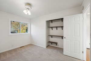 Unfurnished bedroom featuring crown molding, light colored carpet, and a closet