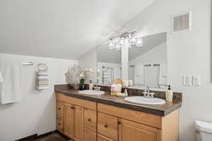 Full bathroom featuring double vanity and vaulted ceiling