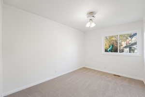 Empty room featuring ornamental molding and light colored carpet