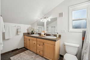 Bathroom featuring double vanity, vaulted ceiling, and a chandelier