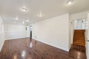Empty room featuring dark wood-style flooring and stairway