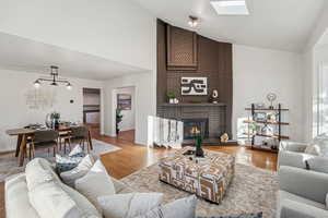 Living room featuring wood finished floors, a brick fireplace, and high vaulted ceiling