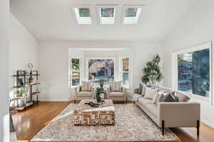 Living room with wood finished floors, lofted ceiling, and a skylight