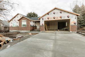 Property under construction featuring brick siding, concrete driveway, and an attached garage