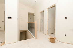 Corridor featuring an upstairs landing and vaulted ceiling