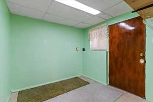 Unfurnished room featuring baseboards and a drop ceiling