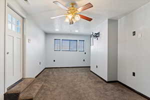 Unfurnished room featuring carpet, ceiling fan, and a textured ceiling