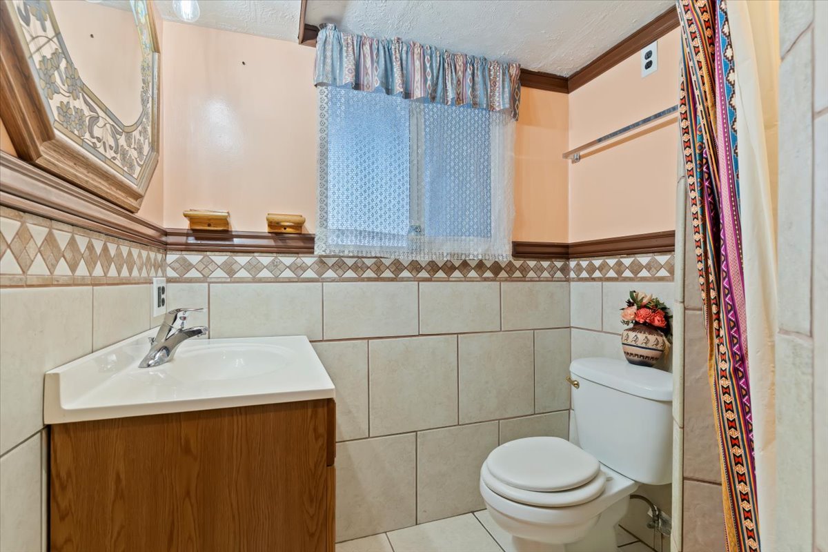 Bathroom featuring vanity, tile patterned flooring, a textured ceiling, and tile walls