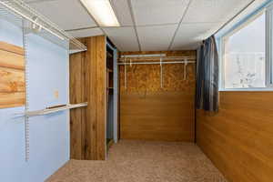Spacious closet with carpet and a drop ceiling