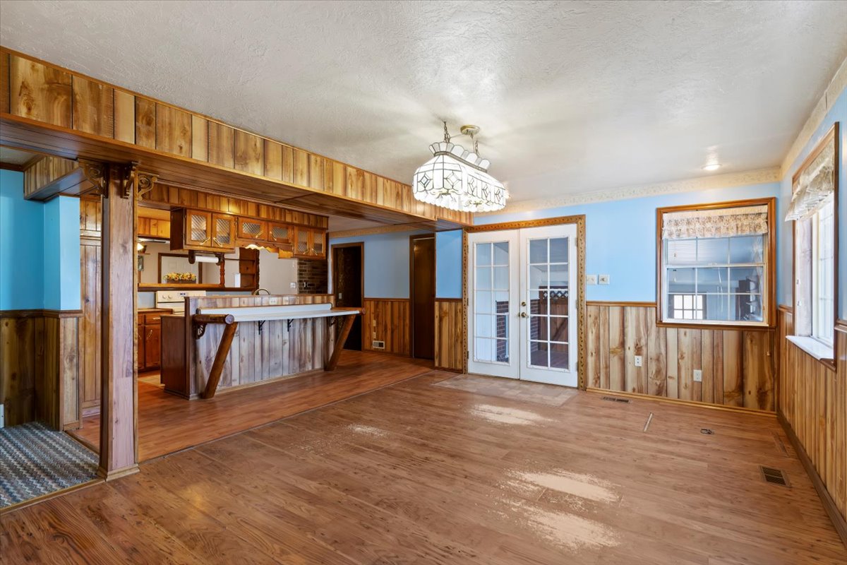 Kitchen with a wainscoted wall, wooden walls, french doors, dark wood-style floors, and light countertops