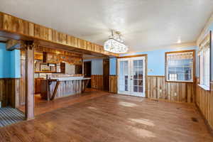 Kitchen with a wainscoted wall, wooden walls, french doors, dark wood-style floors, and light countertops