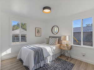 Bedroom with multiple windows and light wood-style flooring