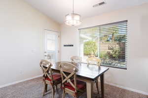 Dining room featuring carpet floors, lofted ceiling, plenty of natural light, and a chandelier
