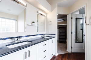 Full bath featuring double vanity and dark wood finished floors