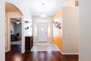 Foyer featuring arched walkways, light wood-style flooring, and a ceiling fan