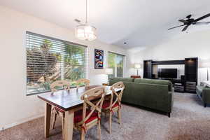 Carpeted dining space featuring lofted ceiling and ceiling fan
