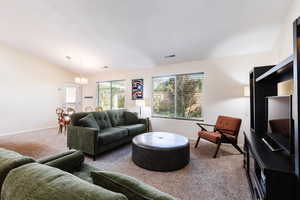 Carpeted living room featuring vaulted ceiling and baseboards