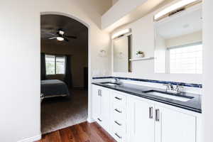 Full bath featuring ensuite bathroom, double vanity, dark wood-style floors, ceiling fan, and plenty of natural light