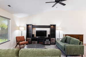 Living area with lofted ceiling, carpet floors, ceiling fan, and a fireplace