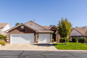 Ranch-style home featuring a front lawn, a tiled roof, concrete driveway, brick siding, and a garage