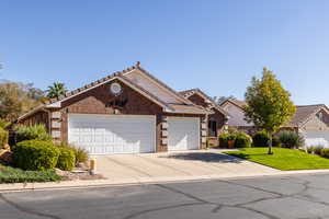 Ranch-style house featuring driveway, an attached garage, a tiled roof, brick siding, and a front yard