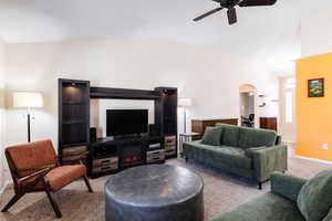 Living area with carpet, arched walkways, a ceiling fan, and high vaulted ceiling