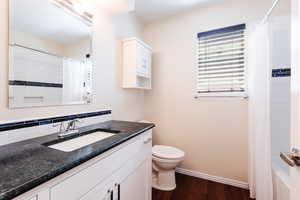 Bathroom with dark wood-style floors, vanity, and shower / bath combo