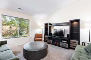 Carpeted living room featuring vaulted ceiling and baseboards