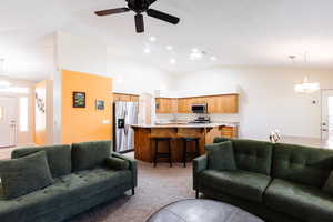 Living room with vaulted ceiling, light colored carpet, and ceiling fan