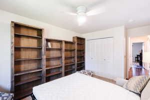 Bedroom featuring dark colored carpet, ceiling fan, and a closet