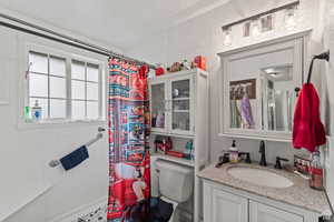 Bathroom featuring a tile shower, a textured wall, and vanity