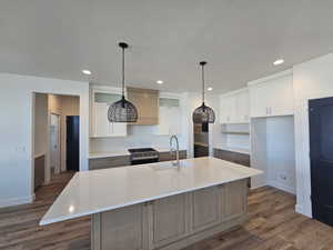 Kitchen featuring dark wood finished floors, decorative light fixtures, white cabinets, stainless steel range, and recessed lighting