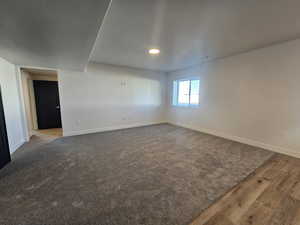 Spare room with dark wood finished floors and dark colored carpet