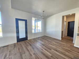 Unfurnished dining area with a chandelier and wood finished floors