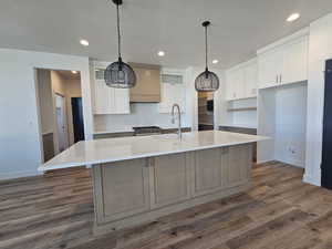 Kitchen featuring white cabinetry, dark wood finished floors, an island with sink, hanging light fixtures, and recessed lighting