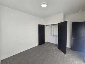 Unfurnished bedroom with dark colored carpet and a closet