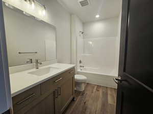 Bathroom with dark wood-style floors, vanity, shower / bath combination, and recessed lighting