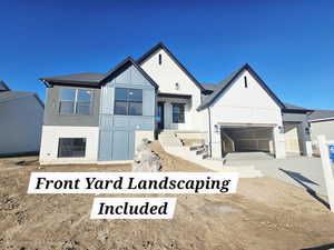 Modern farmhouse with brick siding, a garage, driveway, board and batten siding, and a shingled roof