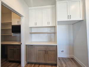 Kitchen featuring dark wood-style flooring, white cabinetry, and tasteful backsplash