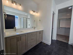 Bathroom with a spacious closet, a shower stall, and double vanity