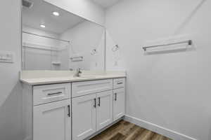 Bathroom with vanity, dark wood-style flooring, a shower, and recessed lighting