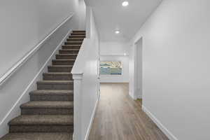 Stairway with wood finished floors and recessed lighting