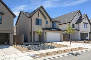 View of front of house with an attached garage, concrete driveway, and stucco siding