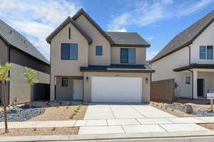 View of front of property featuring concrete driveway, stucco siding, a tiled roof, and a garage
